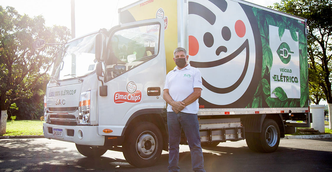 A PepsiCo driver stands proudly in front of his electric powered truck.